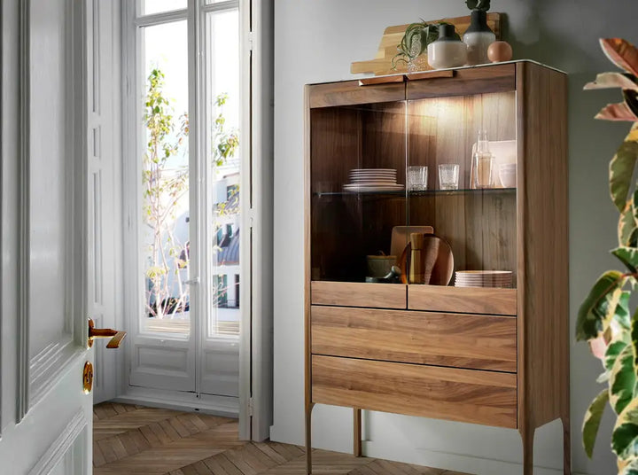 Aparador alto de diseño moderno con estructura de madera chapada en nogal natural y unas originales patas de madera chapada en nogal natural con puertas de vidrio