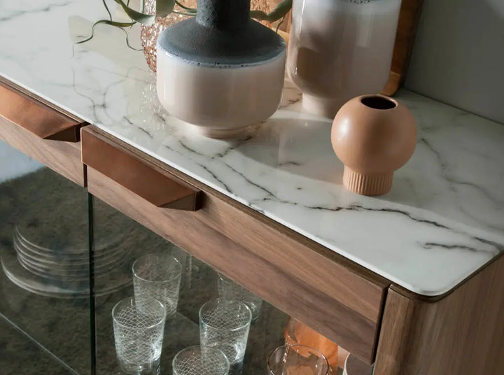 Aparador alto de diseño moderno con estructura de madera chapada en nogal natural y unas originales patas de madera chapada en nogal natural con puertas de vidrio y tapa de marmol