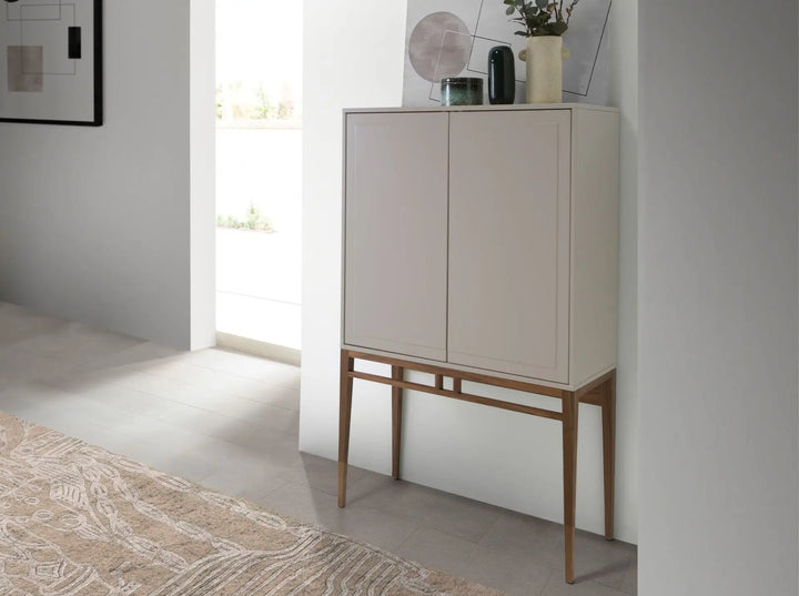 Aparador alto de diseño moderno con estructura de madera de MDF color beige y unas originales patas de madera chapada en nogal natural. 