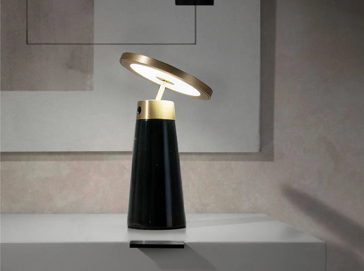Lámpara de sobremesa con cuerpo de mármol porcelánico similar nero marquina y disco direccional de acero pulido dorado