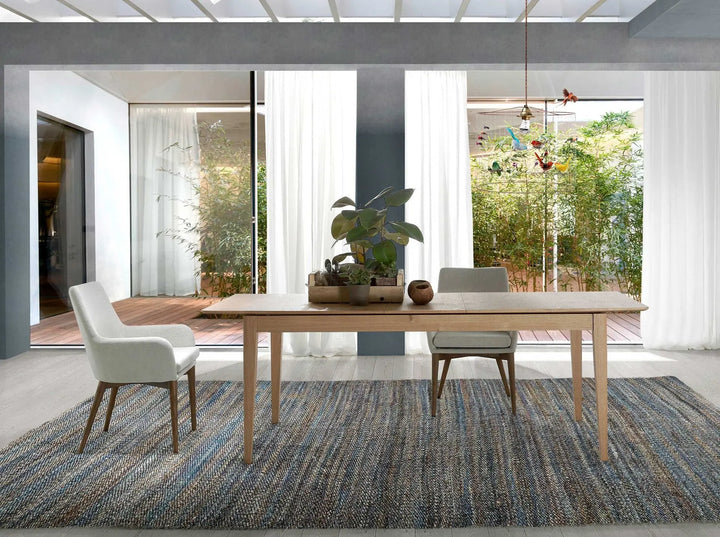 Silla reposabrazos de diseño moderno con asiento y respaldo tapizados en tela color beige. 