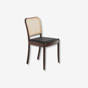 Silla de diseño moderno con asiento tapizado en polipiel color negro y respaldo de rattán.