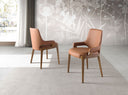 Silla de diseño moderno con asiento y respaldo tapizados en polipiel color marrón.