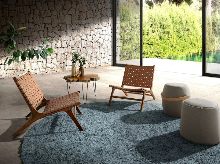 asiento auxiliar tipo puff redondo tapizado en gris, con diseño compacto y funcional