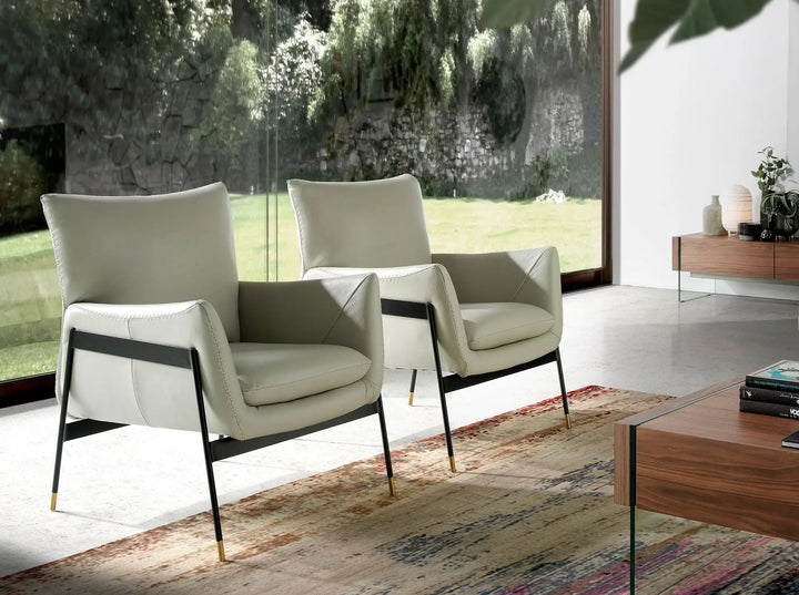 butaca de diseño moderno en piel blanca con patas negras y remates dorados, estilo elegante y minimalista