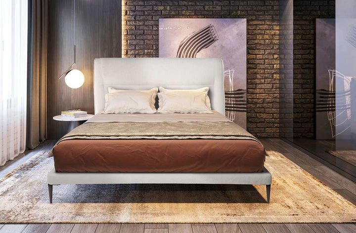 Cama tapizada con cabecero bajo envolvente y patas metálicas – otra vista de ambiente
