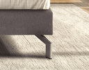 Cama estofada com cabeceira de cantos arredondados e estrado de molas ensacadas de 16 cm – pormenor do pé metálico