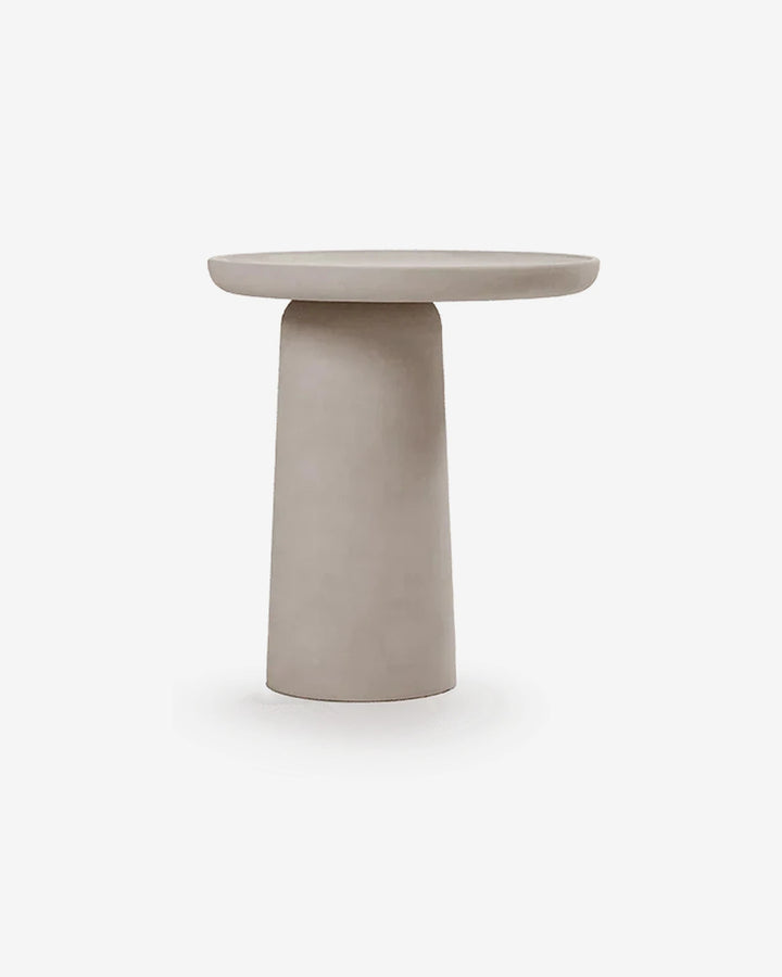 Mesa auxiliar Cala en microcemento sobre fondo gris de estudio