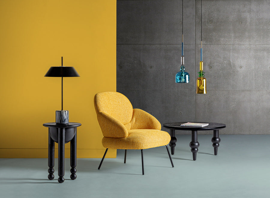 Post-modern setting with yellow wall, exposed concrete and mustard armchair