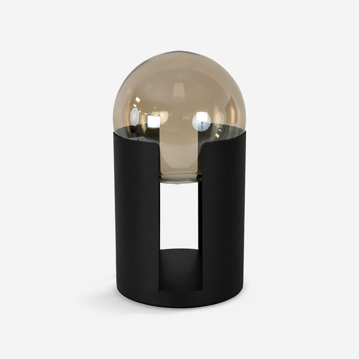 Lámpara sobremesa cristal fumé ámbar y acero negro sobre fondo gris de estudio
