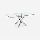 Mesa comedor rectangular de cristal templado con patas de acero en aspa acabado cromado, sobre fondo gris de estudio