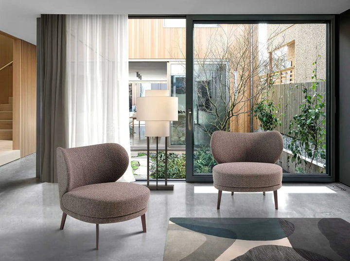 sillon con tapiz texturizado gris, respaldo redondeado y patas de madera en acabado oscuro