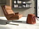 sillón moderno tapizado en piel marrón con estructura metálica curva y diseño ergonómico