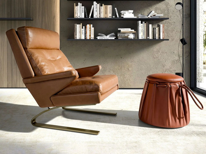 sillón moderno tapizado en piel marrón con estructura metálica curva y diseño ergonómico