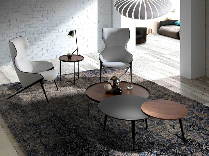 sillón relax con tapizado beige claro, ribeteado en negro y patas metálicas inclinadas