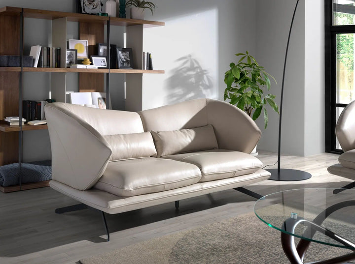 sofá de diseño orgánico en piel color beige con base metálica delgada y forma envolvente contemporánea