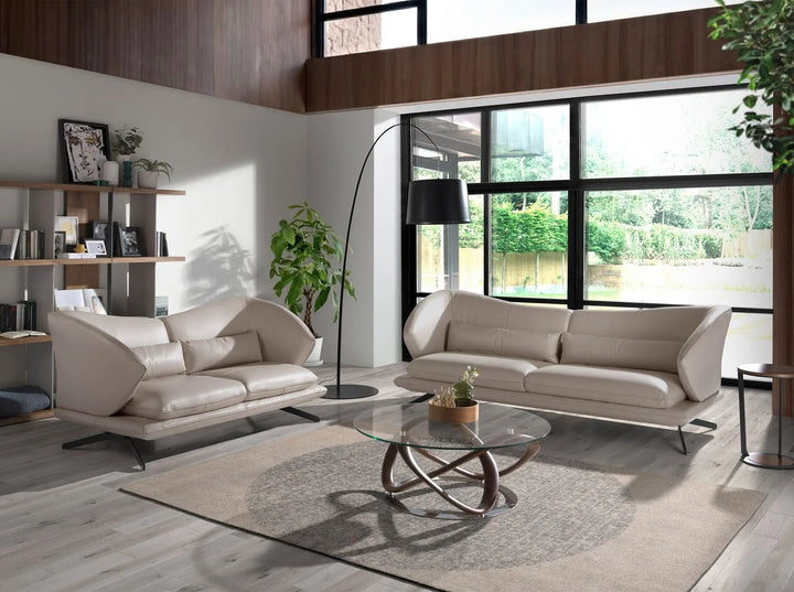 sofá minimalista curvo tapizado en piel beige claro, estructura baja y patas metálicas negras inclinadas